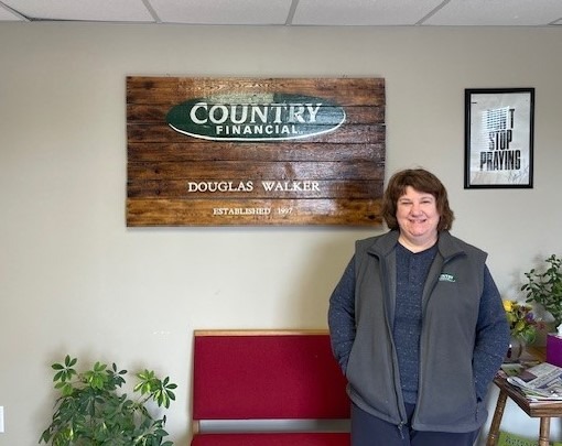 Photo introduces Deanna's success story with The Workforce Connection's On--the-Job Training Program. Photo is of a smiling woman with brown hair wearing a blue shirt and grey vest.