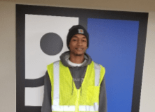 Photo of a man with a grey sweatshit and yellow vest. Story introduces Anthony's success story.