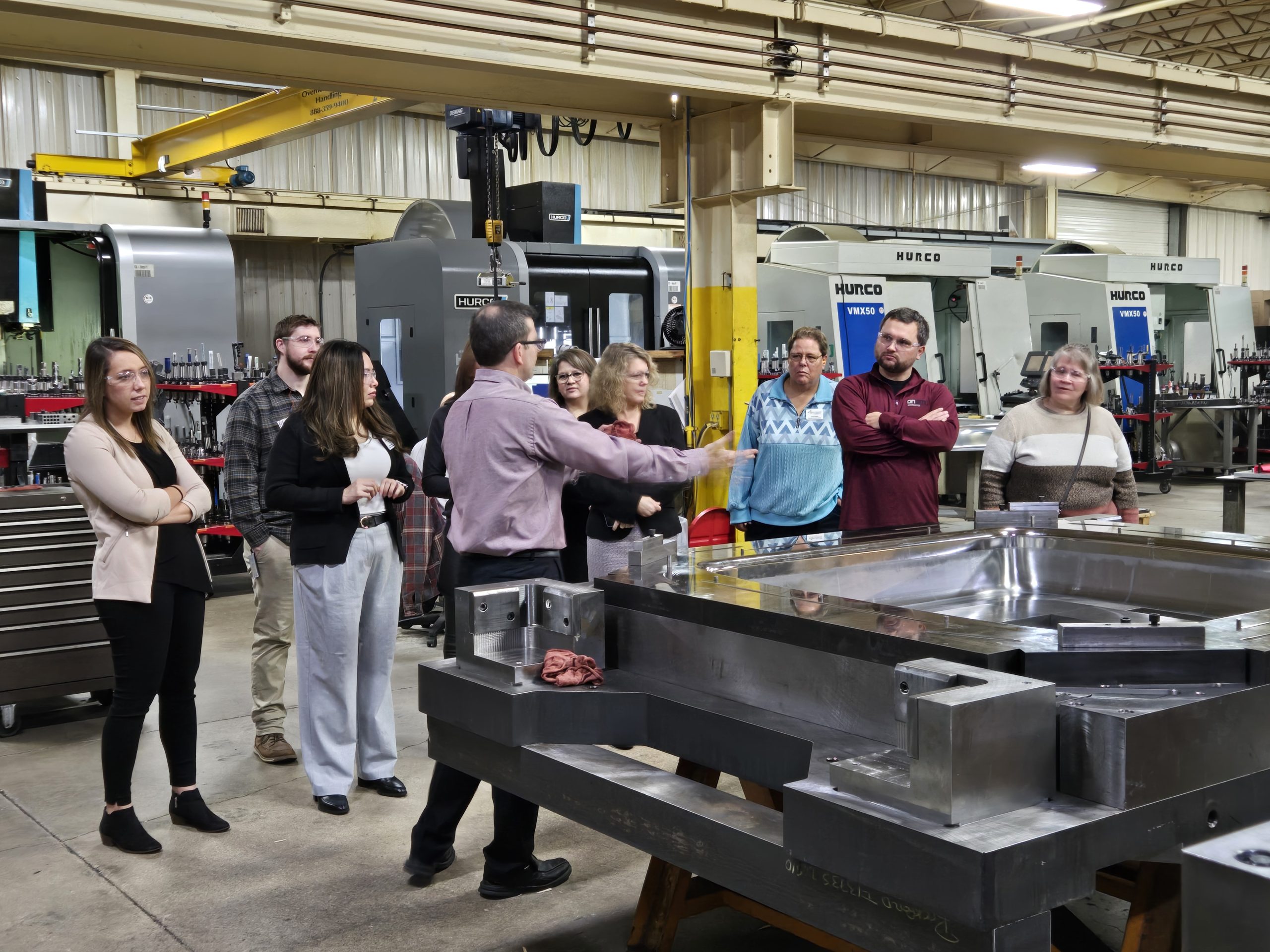 A group standing around a large machine on a tour of Rockford Toolcraft